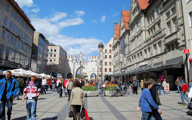 2 - A bustling pedestrian shopping street in Munich viewed from Karlsplatz towards the historic Karlstor gate